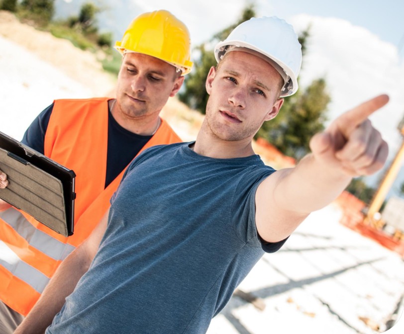 Tømrer og lærling i tømrerfaget snakker sammen om et byggeprosjekt
