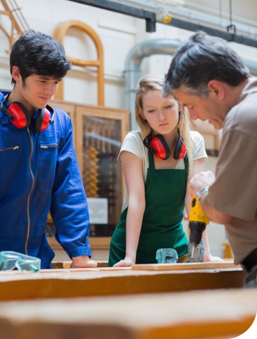 En tømrer har opplæring med to lærlinger i tømrerfaget